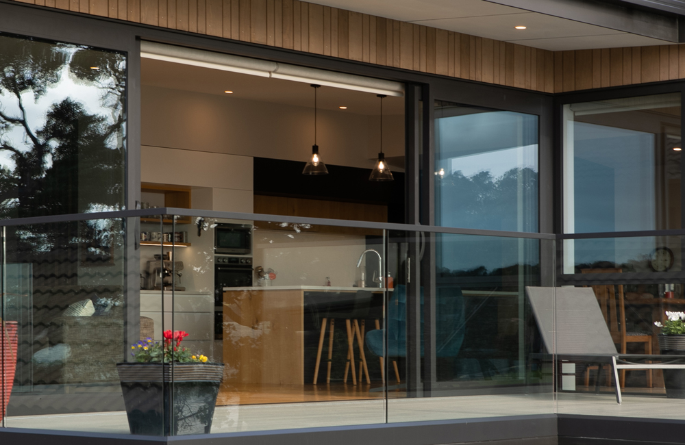 Modern home in Warkworth NZ with reflective glass sliding doors and windows, offering privacy and a seamless indoor-outdoor flow – Rodney Aluminium.
