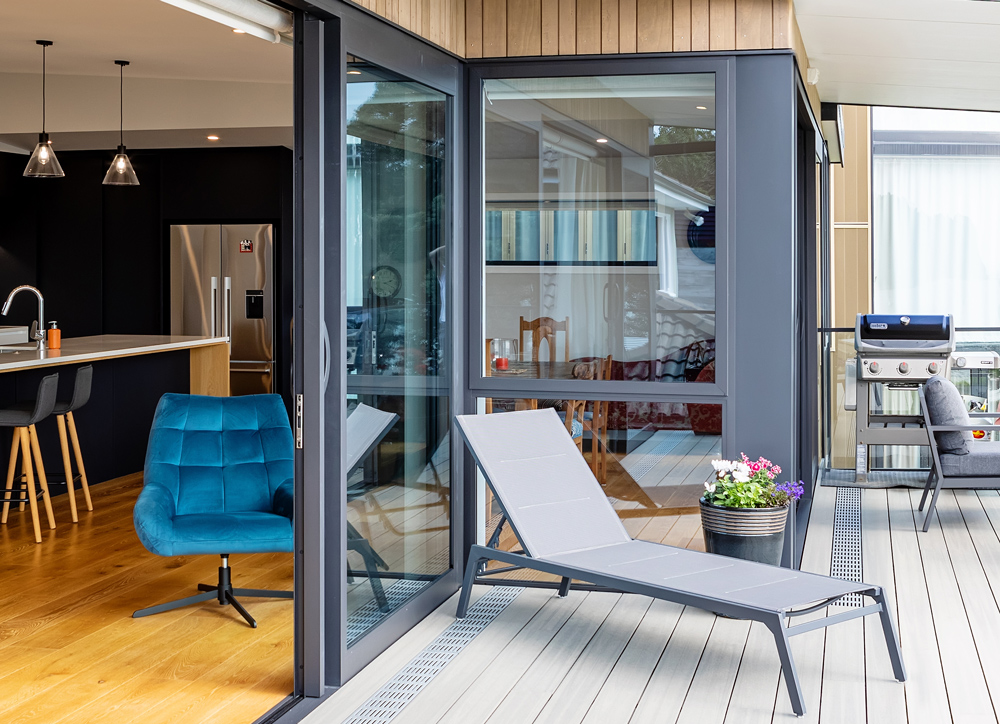 Home with aluminium sliding doors opening to a deck and kitchen view.