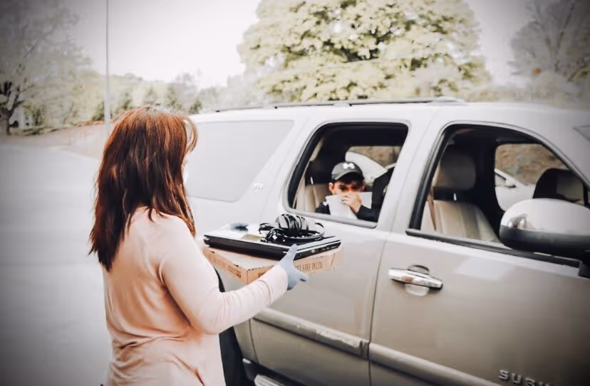 A woman holding technology next to a car