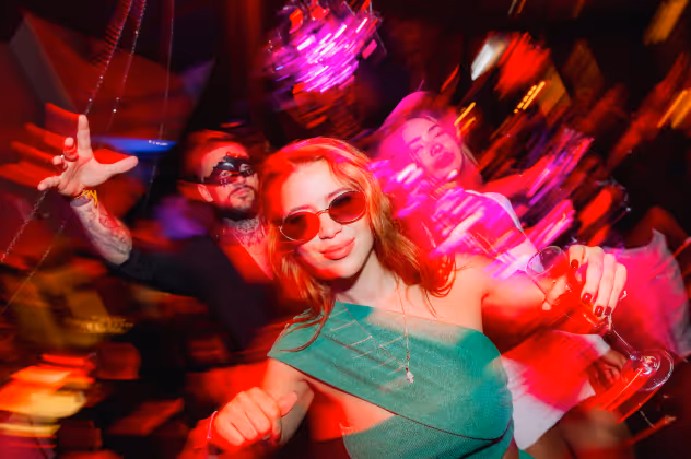 Party guests dancing with drinks at Bonzai nightclub event in Aruba with neon lights and lively atmosphere