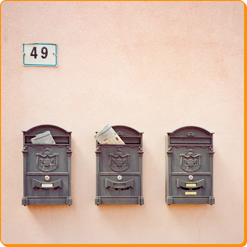 Three grey ornate mailboxes on a pink wall with the number 49