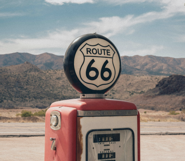 A classic Route 66 gas pump in a desert setting with mountains in the background.