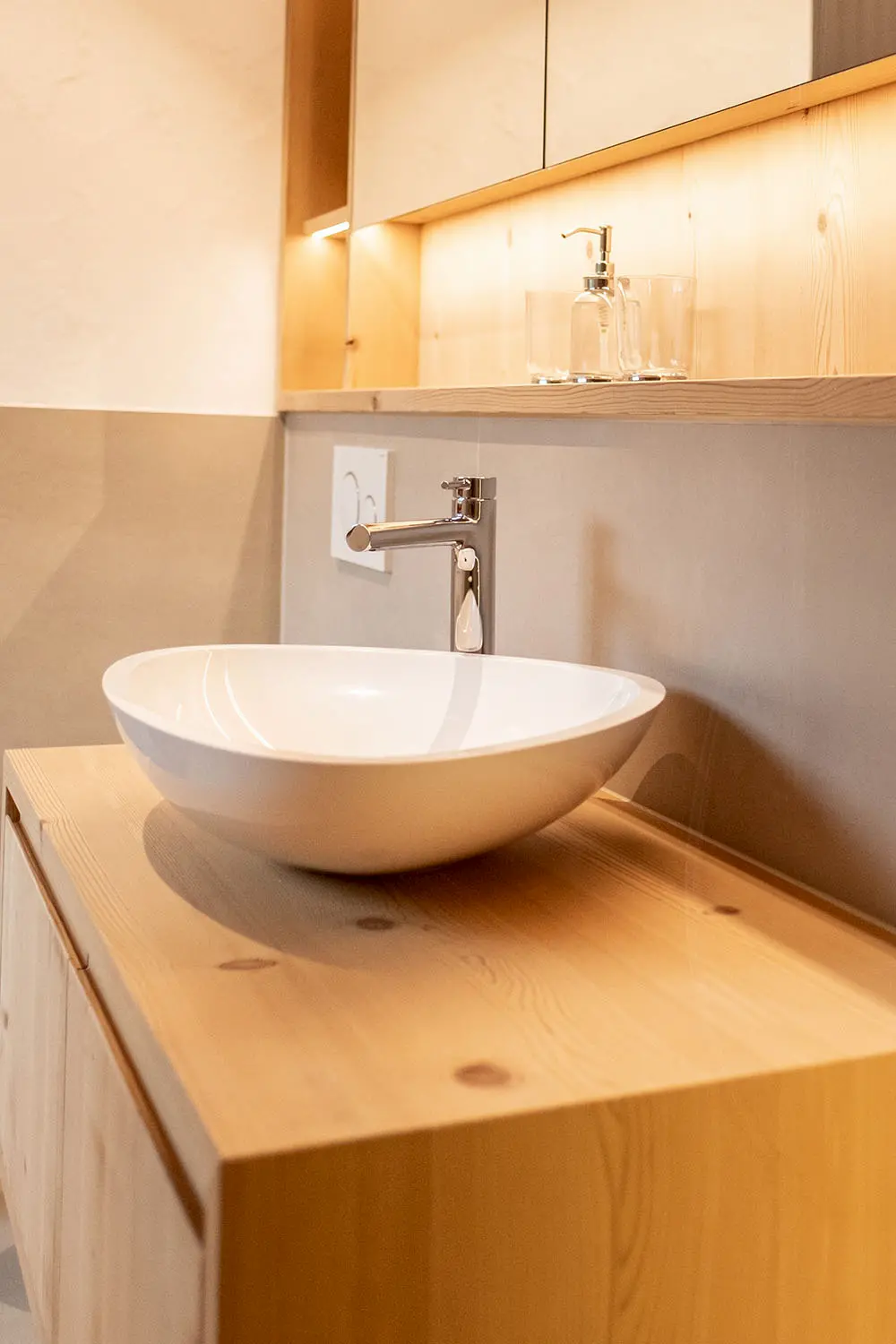 Modernes Einbaumöbel aus Massivholz in einem WC, mit aufgesetztem ovalem Lavabo – hochwertiges Badezimmer-Design im Holzbau von Vögeli Holzbau