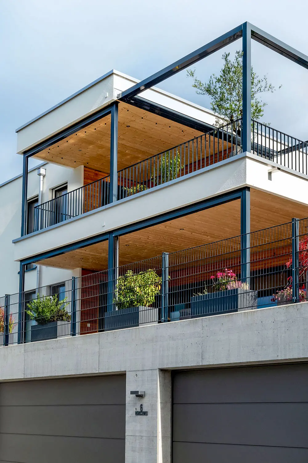 Modernes Holzhaus mit Doppelgarage und holzverkleideten Balkonen – nachhaltige Architektur und moderner Holzbau von Vögeli Holzbau