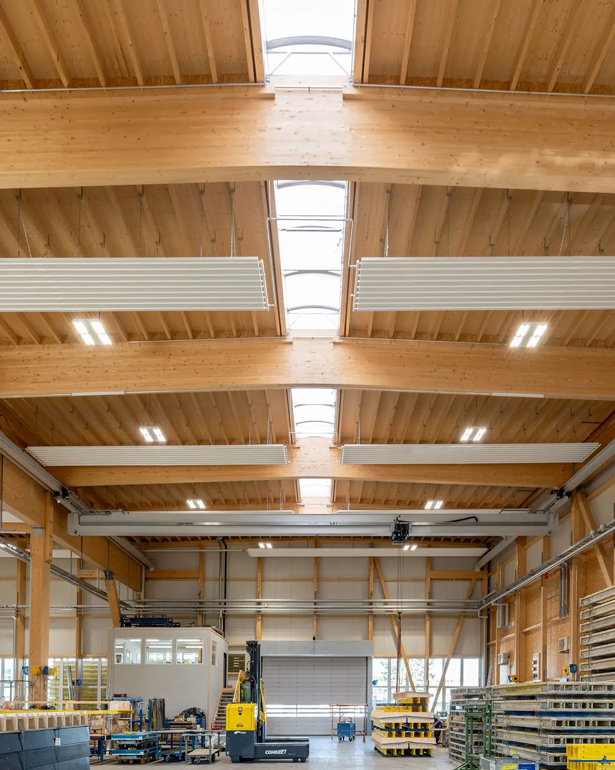Moderne Produktionshalle mit sichtbarer Holztragkonstruktion, großen Oberlichtern und nachhaltiger Bauweise, realisiert von der Vögeli Holzbau AG.