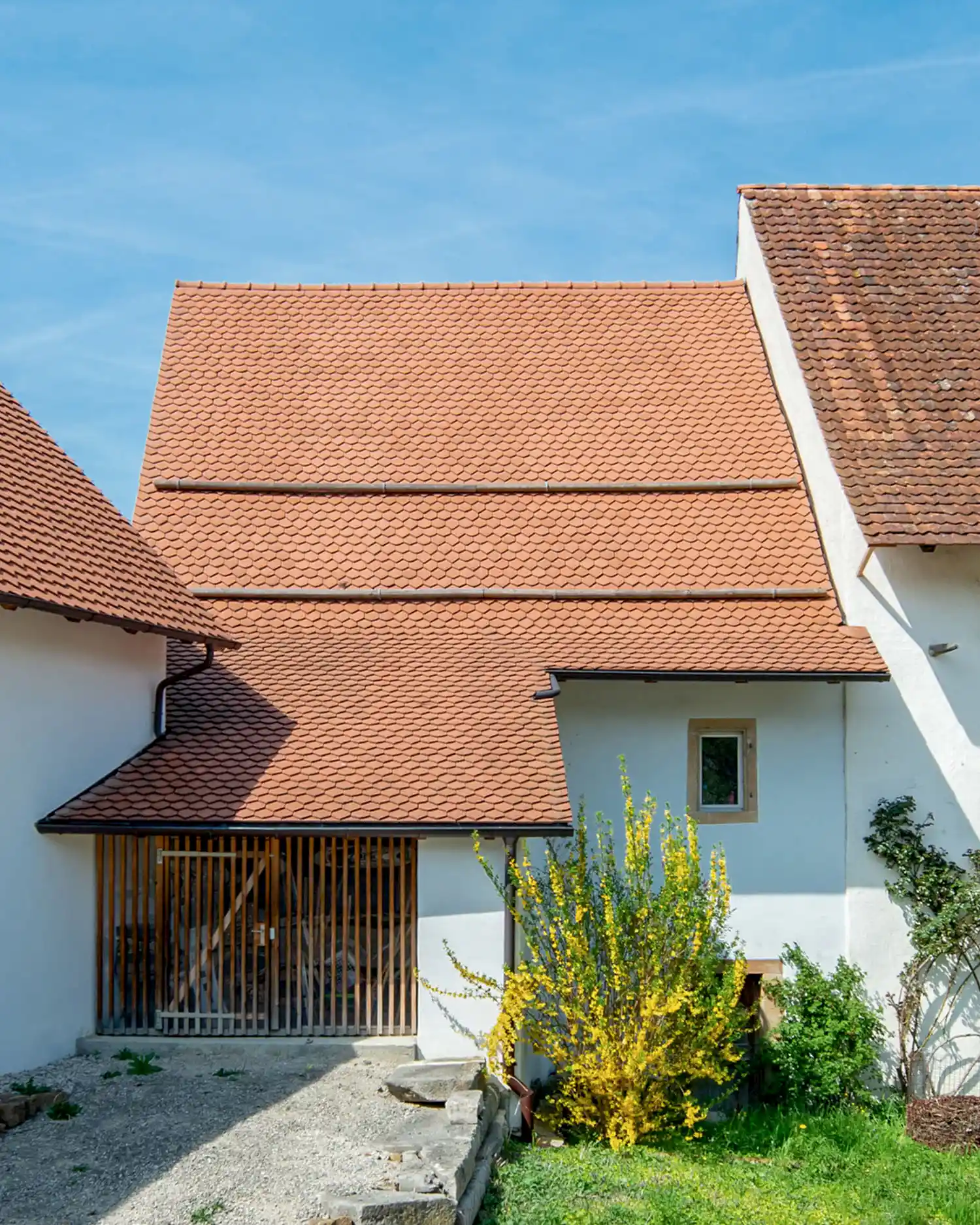 Sanierte historische Bedachung mit roten Ziegeln und hell verputzten Fassaden – traditionelle Architektur sorgfältig restauriert.