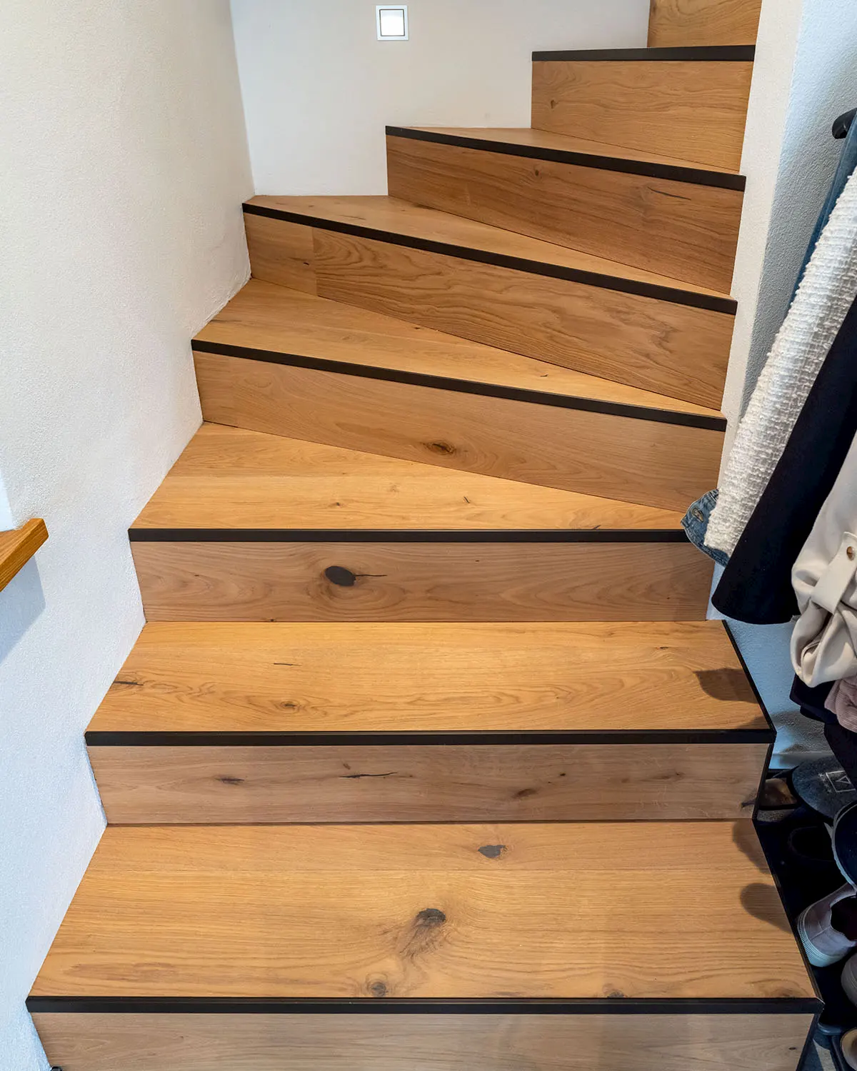 Maßgefertigte Holztreppe mit markanter Maserung und dunklen Akzentlinien – modernes Design trifft auf traditionelles Handwerk.