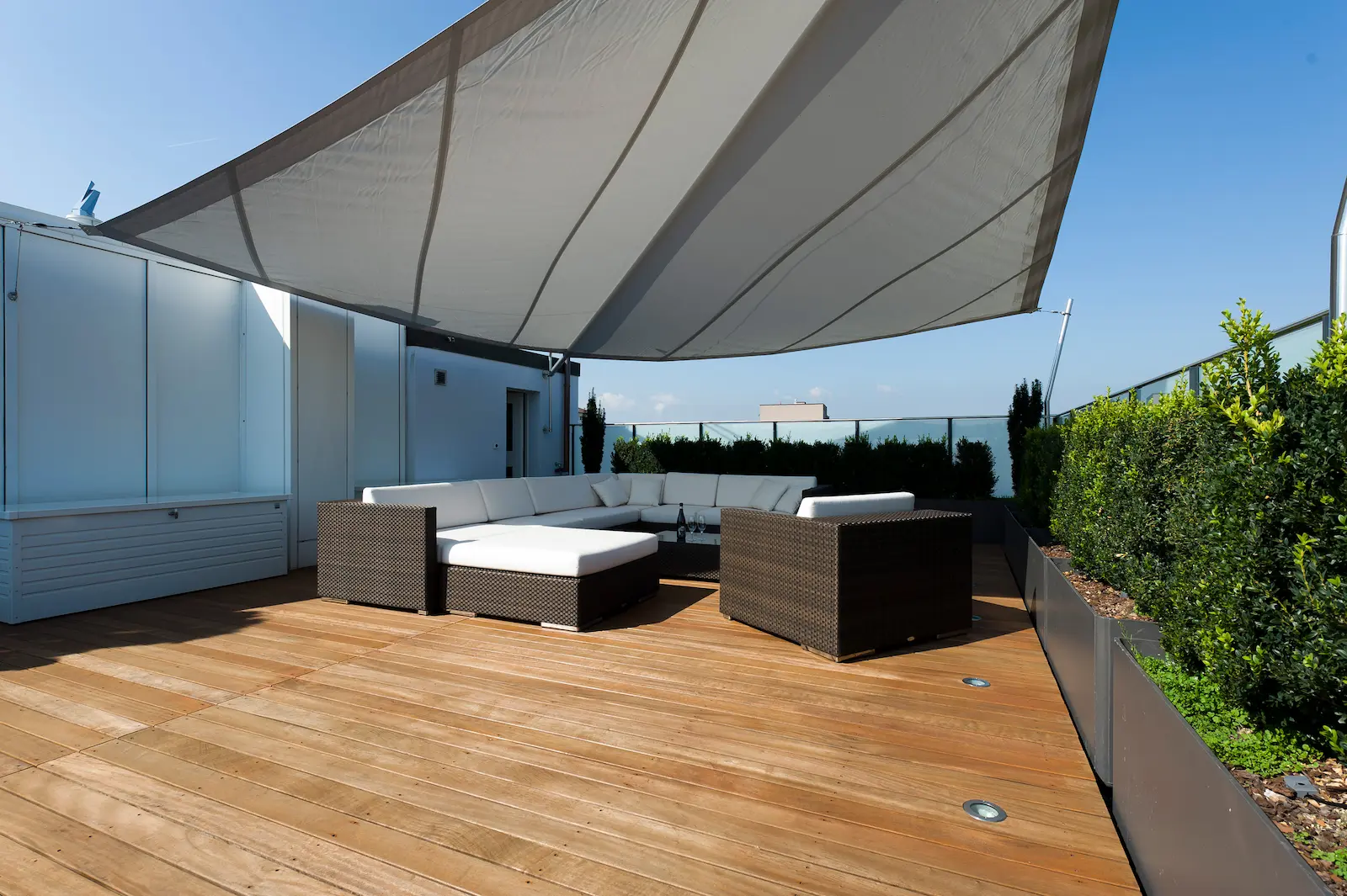 Moderne Dachterrasse mit edlem Sipo-Holzbelag, stilvoller Lounge und Sonnensegel – hochwertige Schreinerarbeit für entspannte Aussenräume.