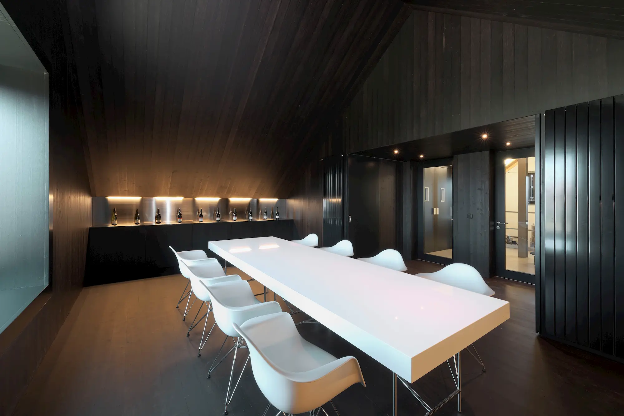 Eleganter Besucherraum mit dunkler Holzverkleidung und modernem Design – Innenausbauprojekt von Vögeli Holzbau.