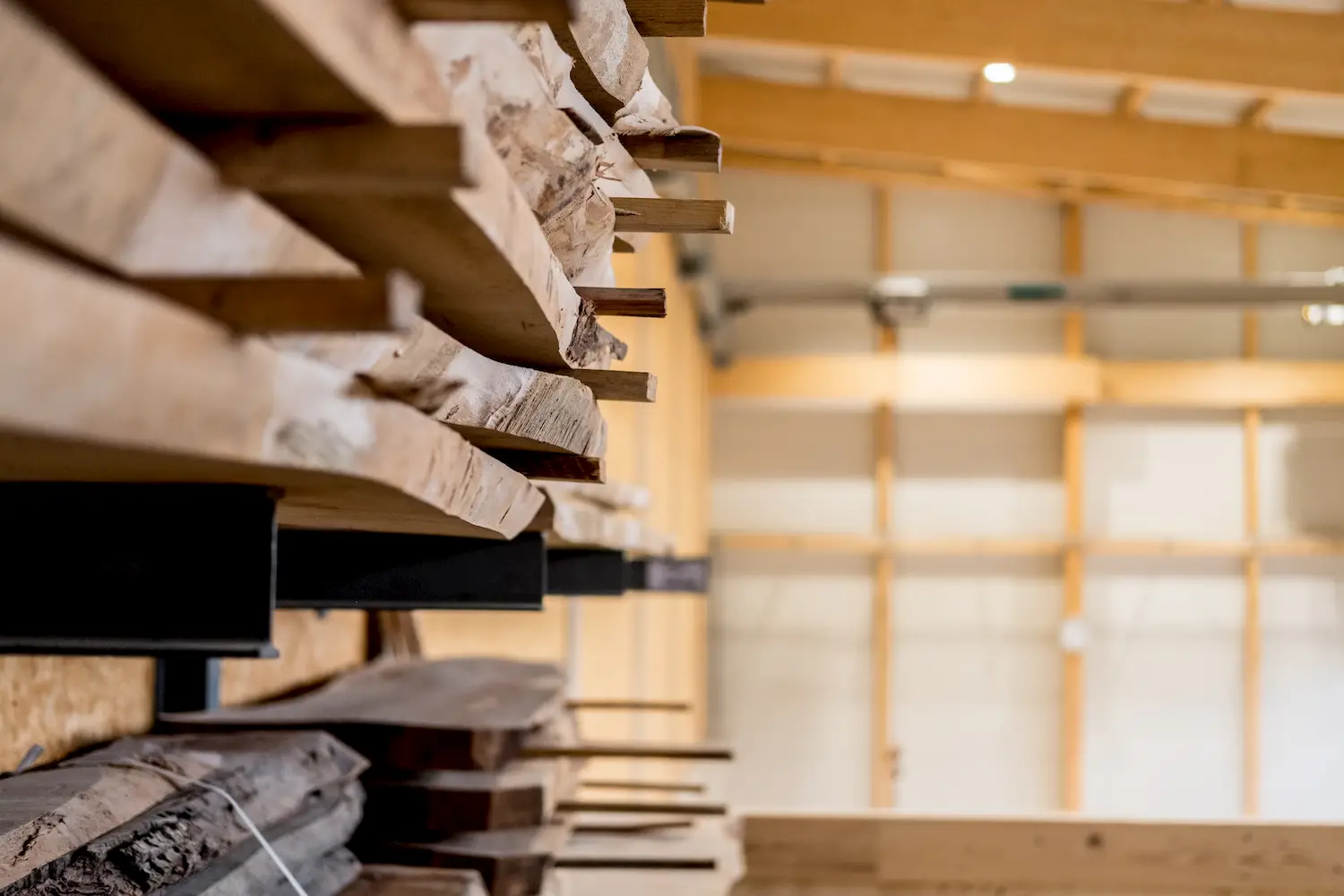 Gestapeltes Altholz im Lager einer modernen Holzbau-Werkhalle – nachhaltige Materialnutzung und sorgfältige Auswahl hochwertiger Hölzer für individuelle Projekte.