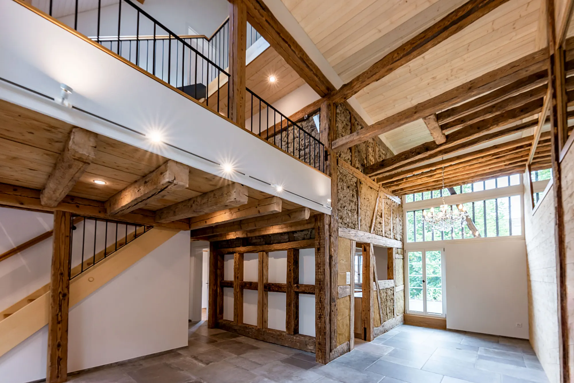 Aufwendig saniertes historisches Tragwerk mit sichtbaren Holzbalken, modernem Innenausbau und hoher Raumwirkung – gelungene Verbindung von Alt und Neu.