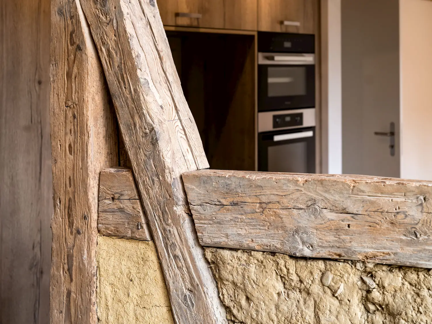 Detailansicht historischer Holzbalken mit Lehmfüllung im sanierten Innenraum – traditionelles Fachwerk trifft auf moderne Wohnarchitektur.