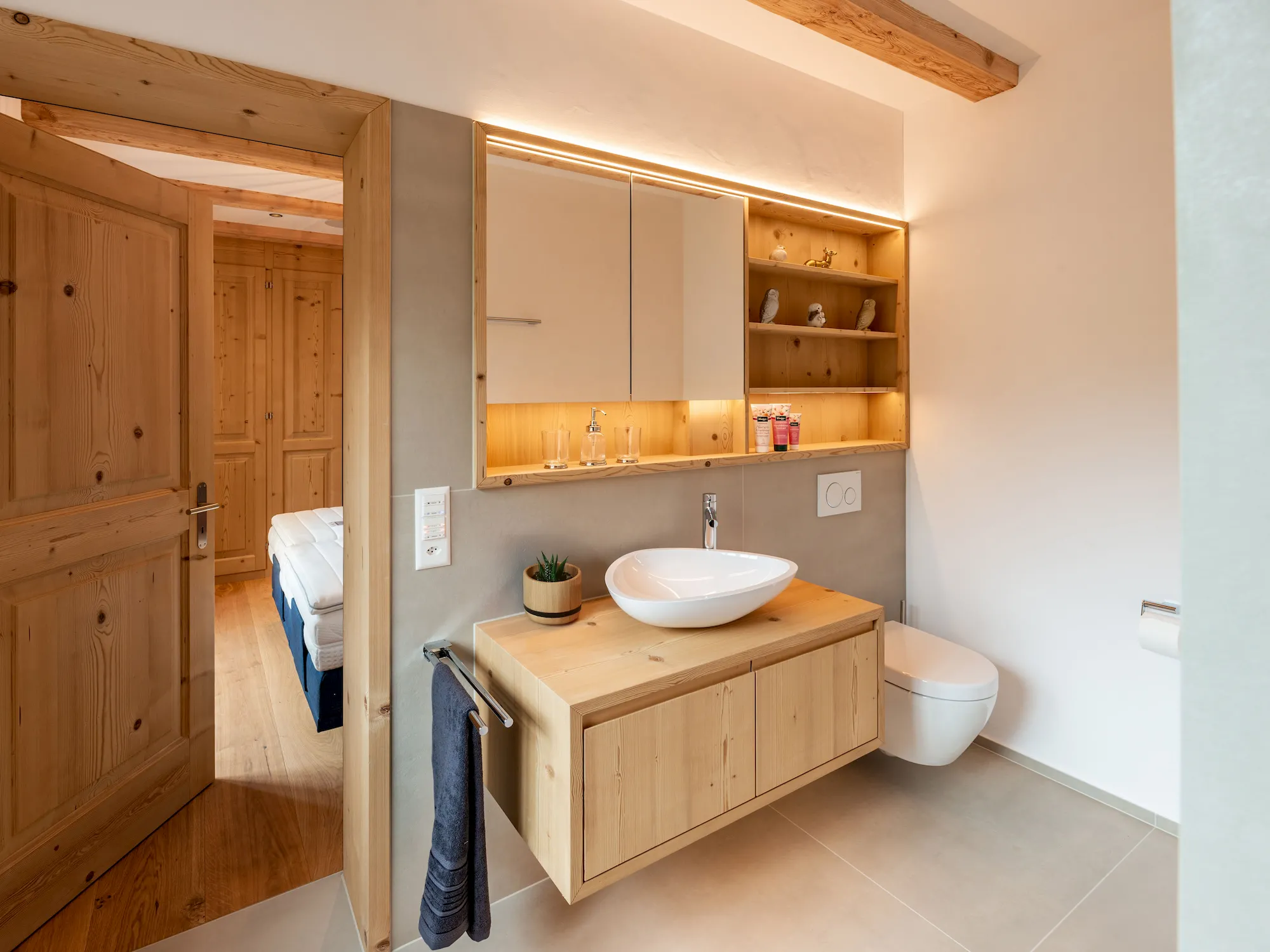 Modernes Badmöbel aus Holz mit Waschbecken, Stauraum und indirekter Beleuchtung – hochwertiger Innenausbau und Schreinerarbeit in natürlichem Design.