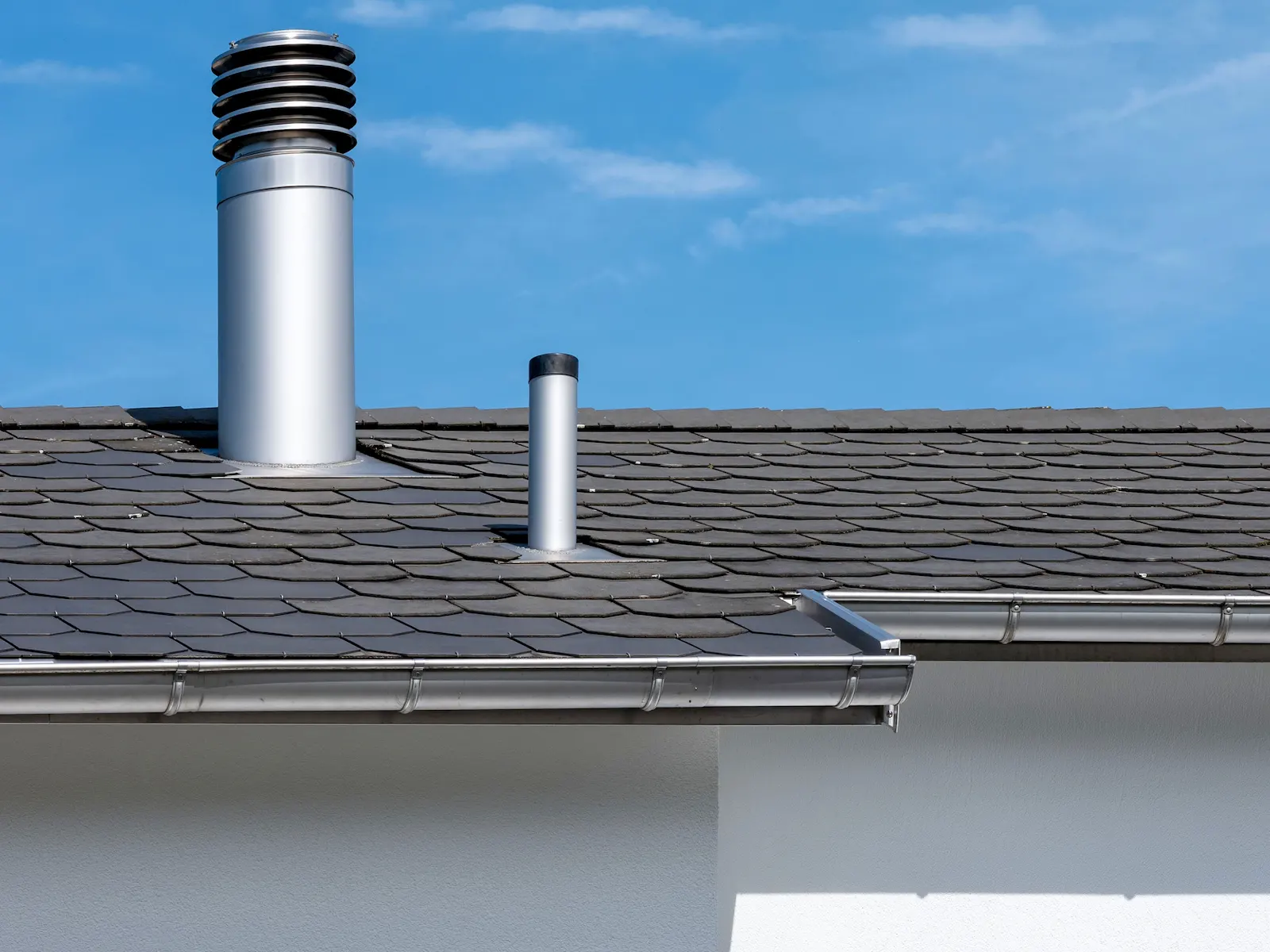 Modernes Dach mit präzisen Spenglerarbeiten aus Edelstahl – Abläufe, Rohre und Kamine in hochwertiger Ausführung für langlebigen Witterungsschutz.