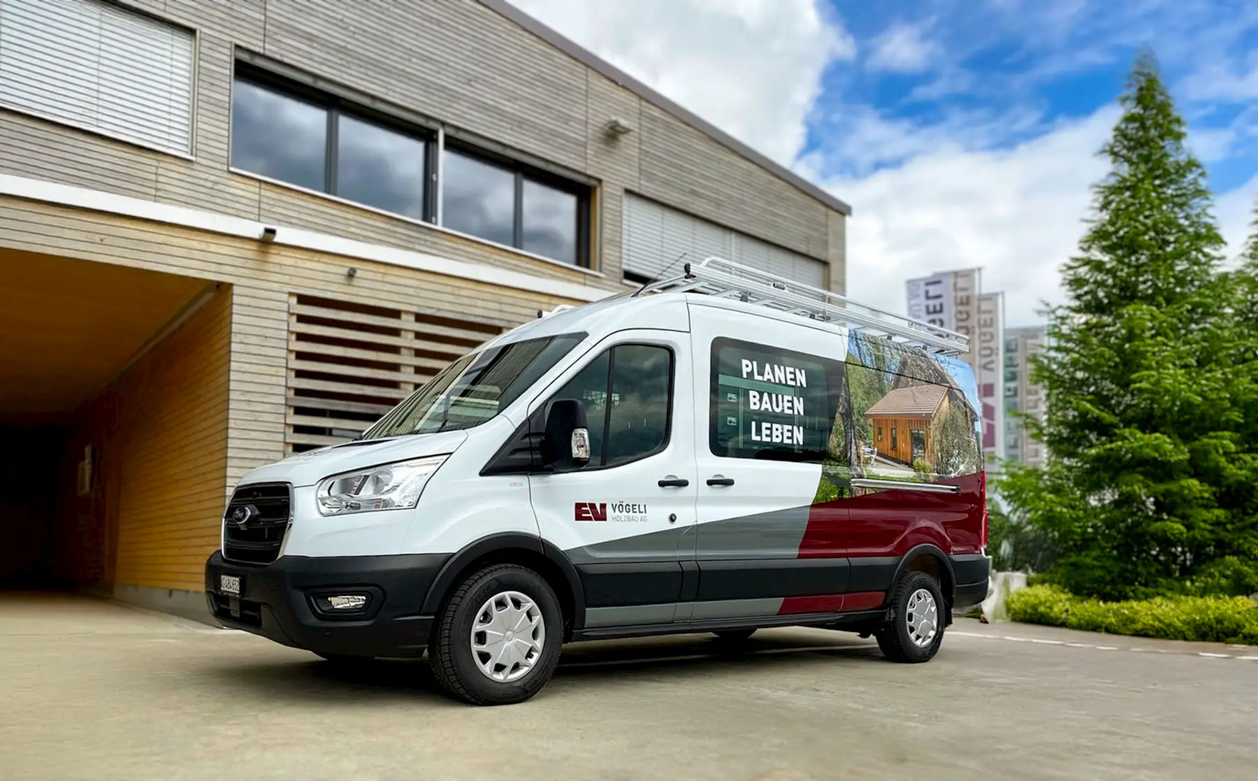 Servicebus der Vögeli Holzbau AG vor dem Firmengebäude in Würenlingen – unterwegs für Planung, Holzbau, Schreinerei, Spenglerei und Servicearbeiten.