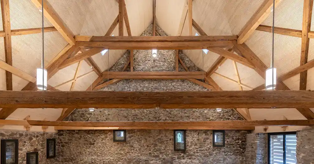 Innenansicht eines historischen Gebäudes mit sichtbaren Holzbalken und Steinmauern.