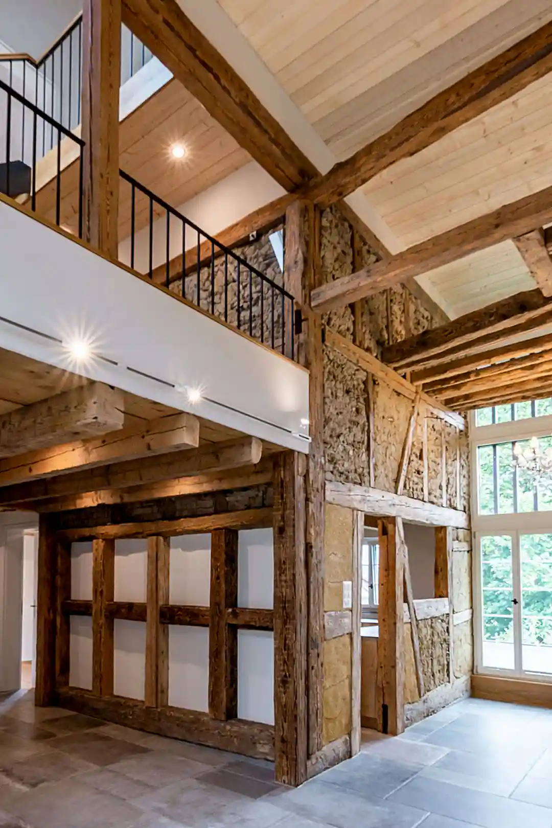 Innenraum eines Hauses mit sichtbaren historischen Holzträgern und großer Fensterfront.
