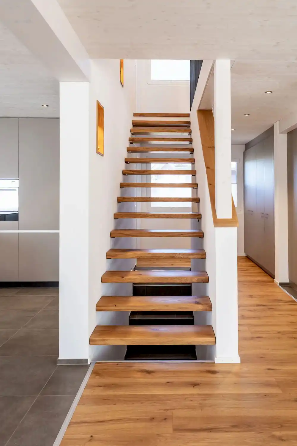 Moderne Holztreppe mit schwebenden Stufen in einem hellen, minimalistischen Innenraum.