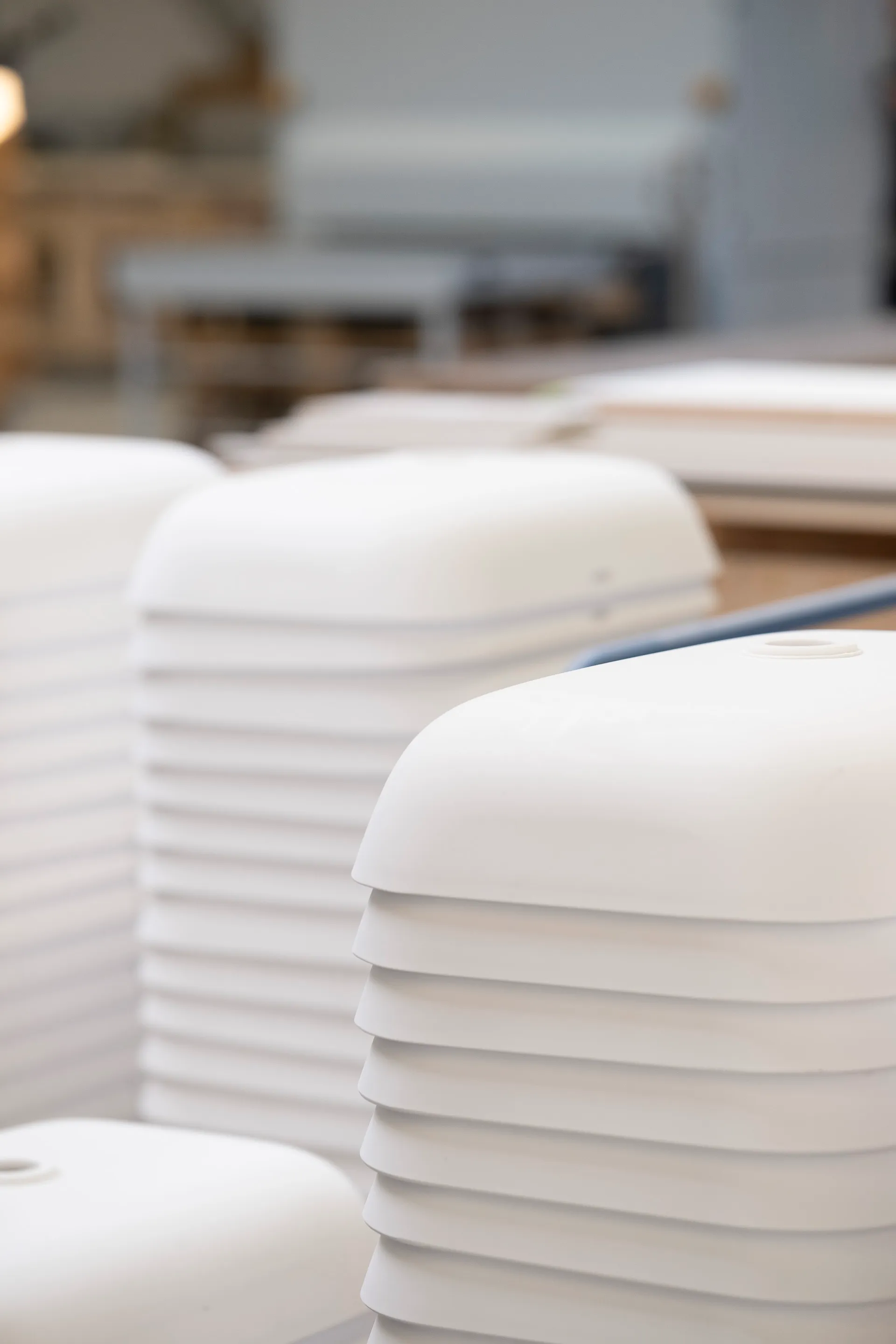 Stacks of white plastic covers with rounded edges placed in an indoor environment.