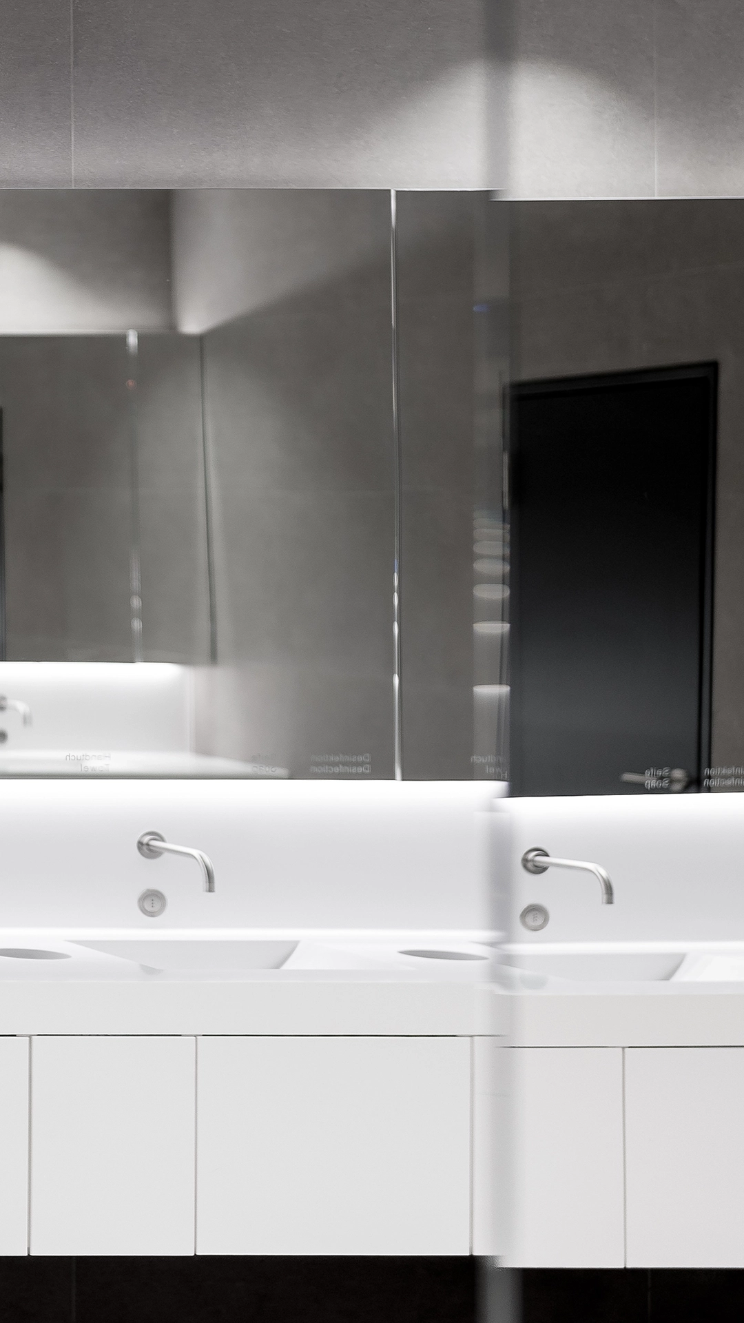 Modern white bathroom sink with dual faucets and large mirrored cabinets above.
