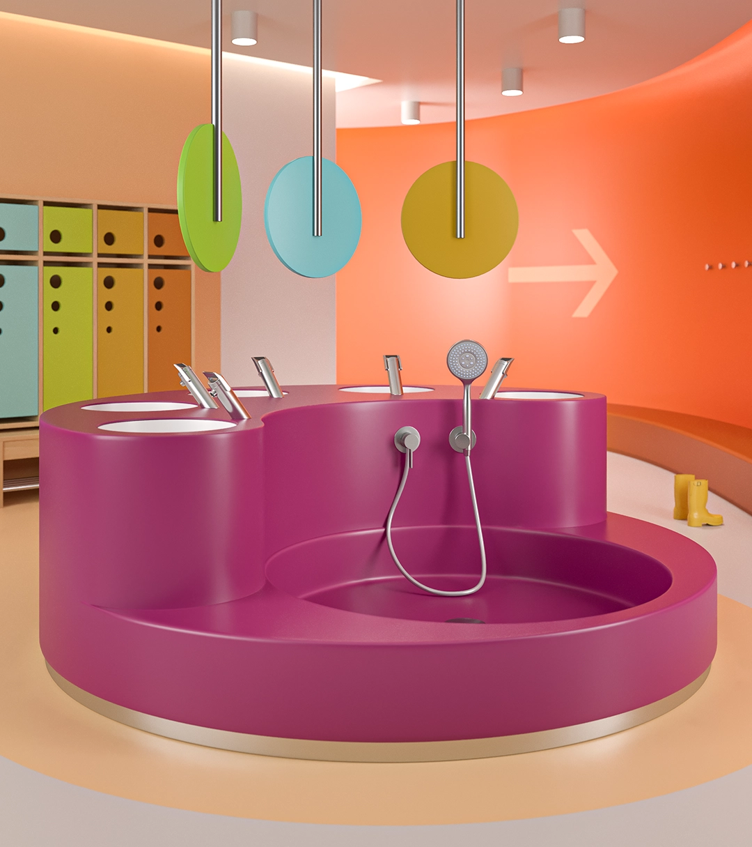 Brightly colored children's washroom with a large pink sink featuring multiple faucets and a handheld shower, colorful lockers, and a curved orange wall with an arrow.