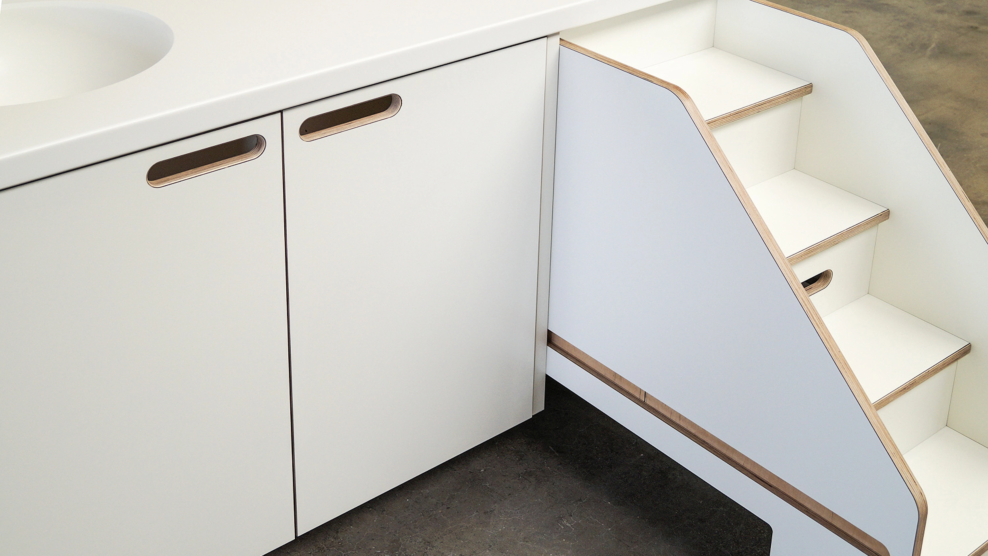 Modern white bathroom cabinet with integrated sink and a small attached staircase with wooden edges.