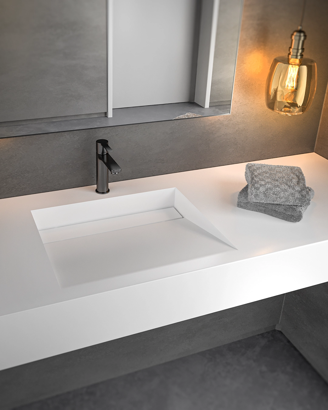 Modern bathroom sink with a sleek black faucet, gray towels stacked on white countertop, and a lit amber pendant light reflecting in a large mirror.