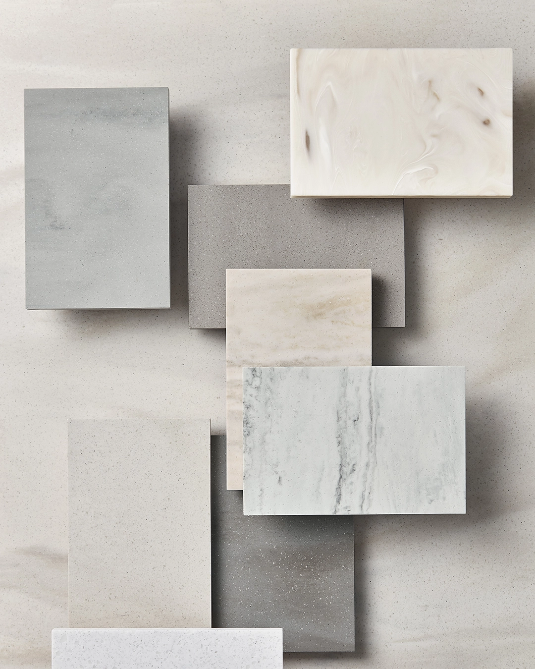 Various rectangular stone and marble tiles in neutral shades arranged on a light surface.