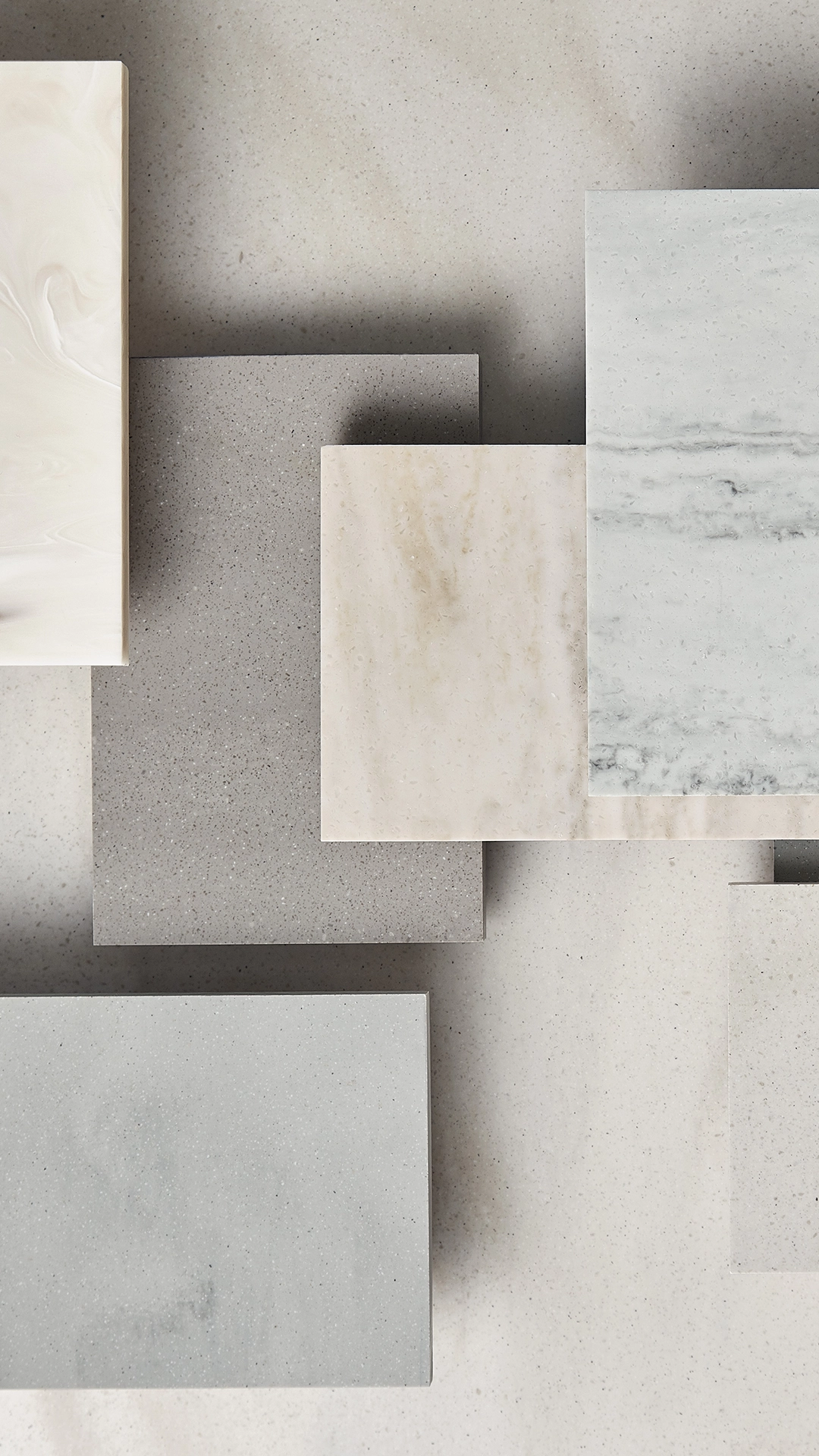 Overlapping rectangular stone slabs in various shades of beige and gray with subtle patterns on a neutral background.
