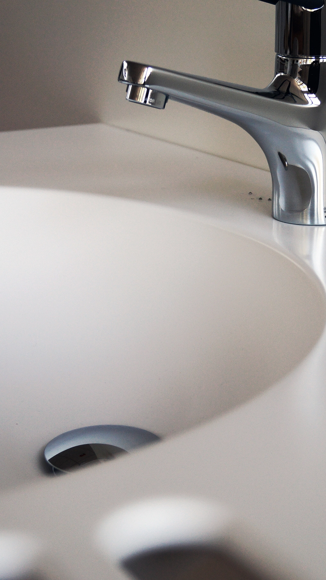 Close-up of a modern chrome faucet mounted on a white sink basin.