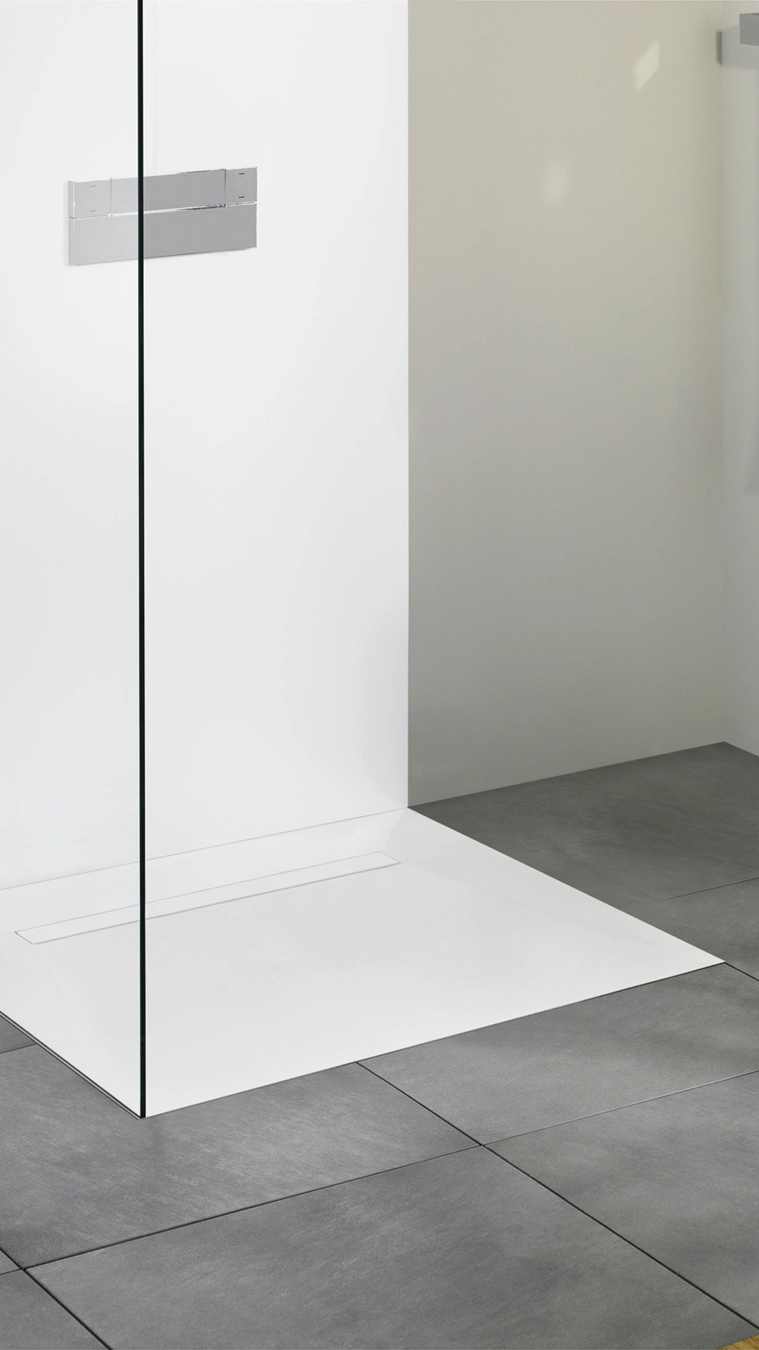 Minimalist walk-in shower with a frameless glass partition, white shower base, and gray floor tiles.