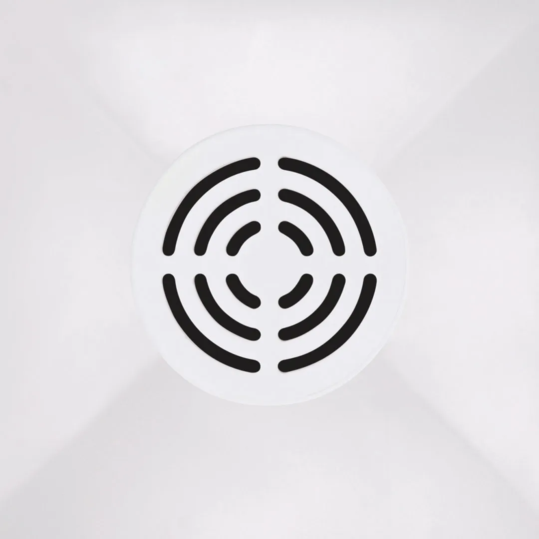 Top-down view of a white circular shower drain with black slot patterns in a white shower base.