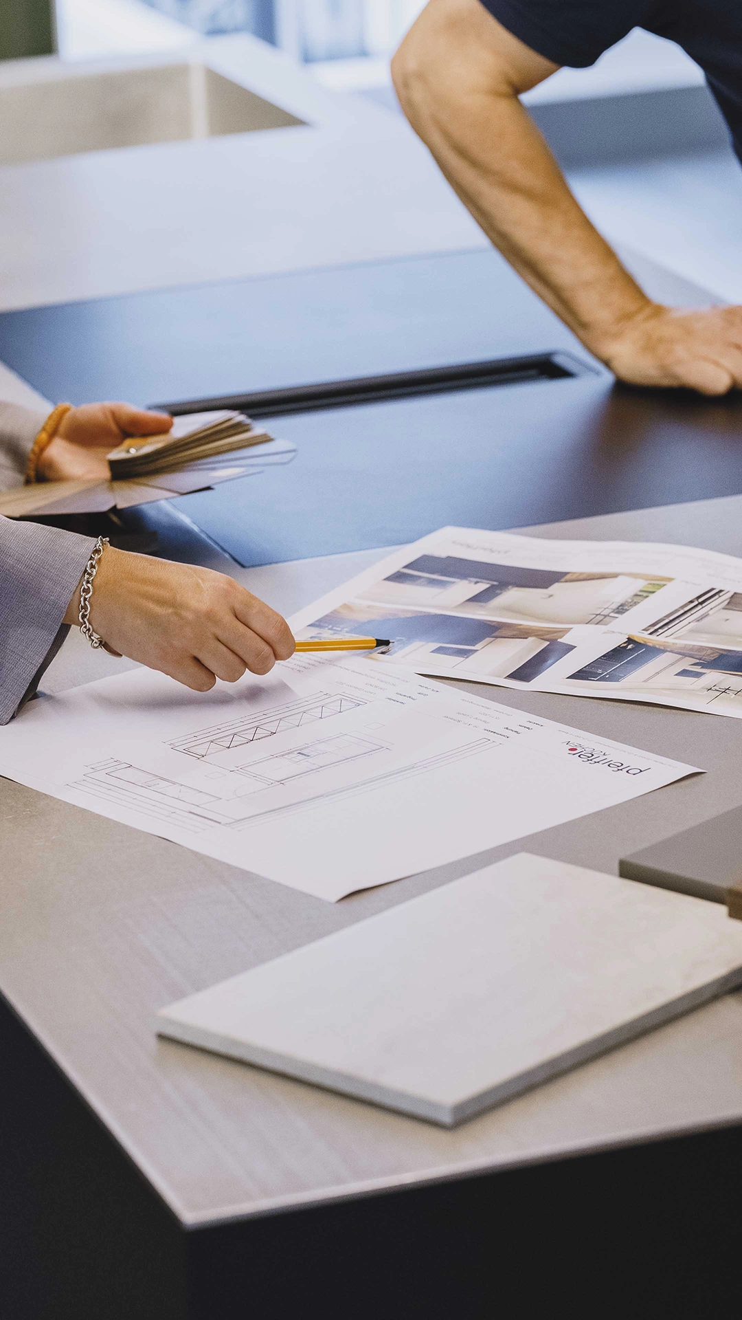 Two people reviewing architectural plans and material samples on a table.
