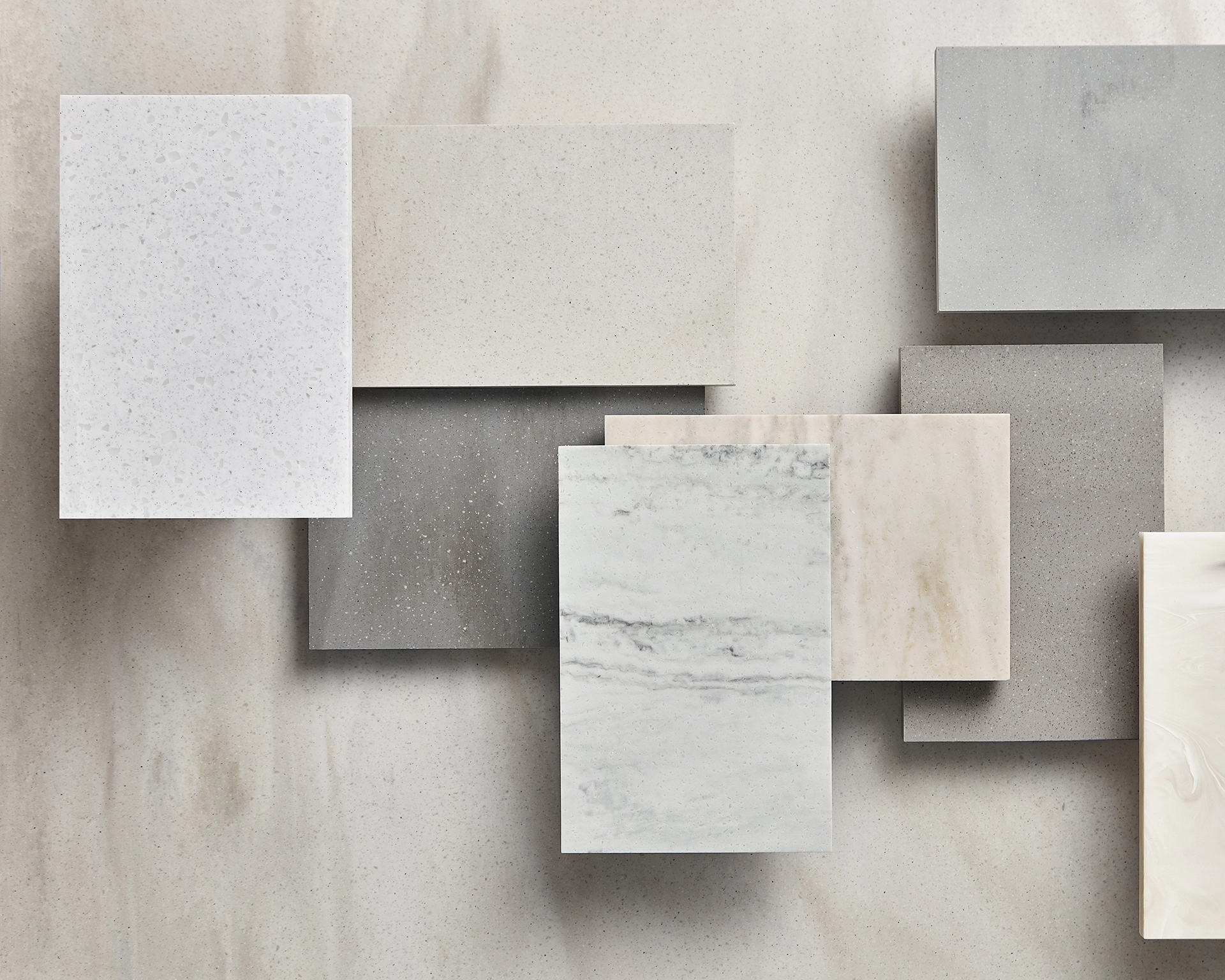Overlapping rectangular stone and quartz samples in various shades of white, gray, and beige with different textures and patterns.