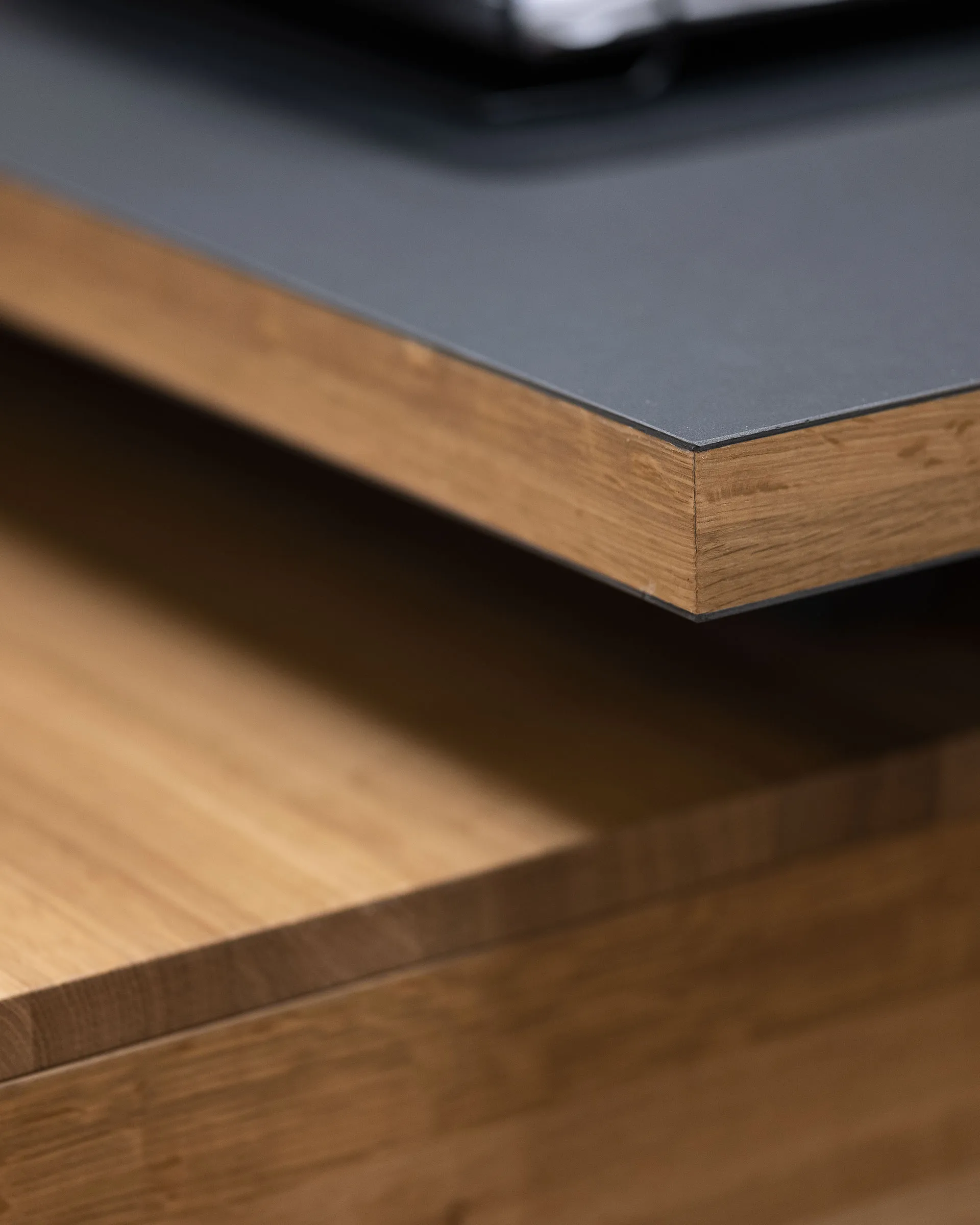 Close-up of a wooden drawer with a black countertop edge above it.