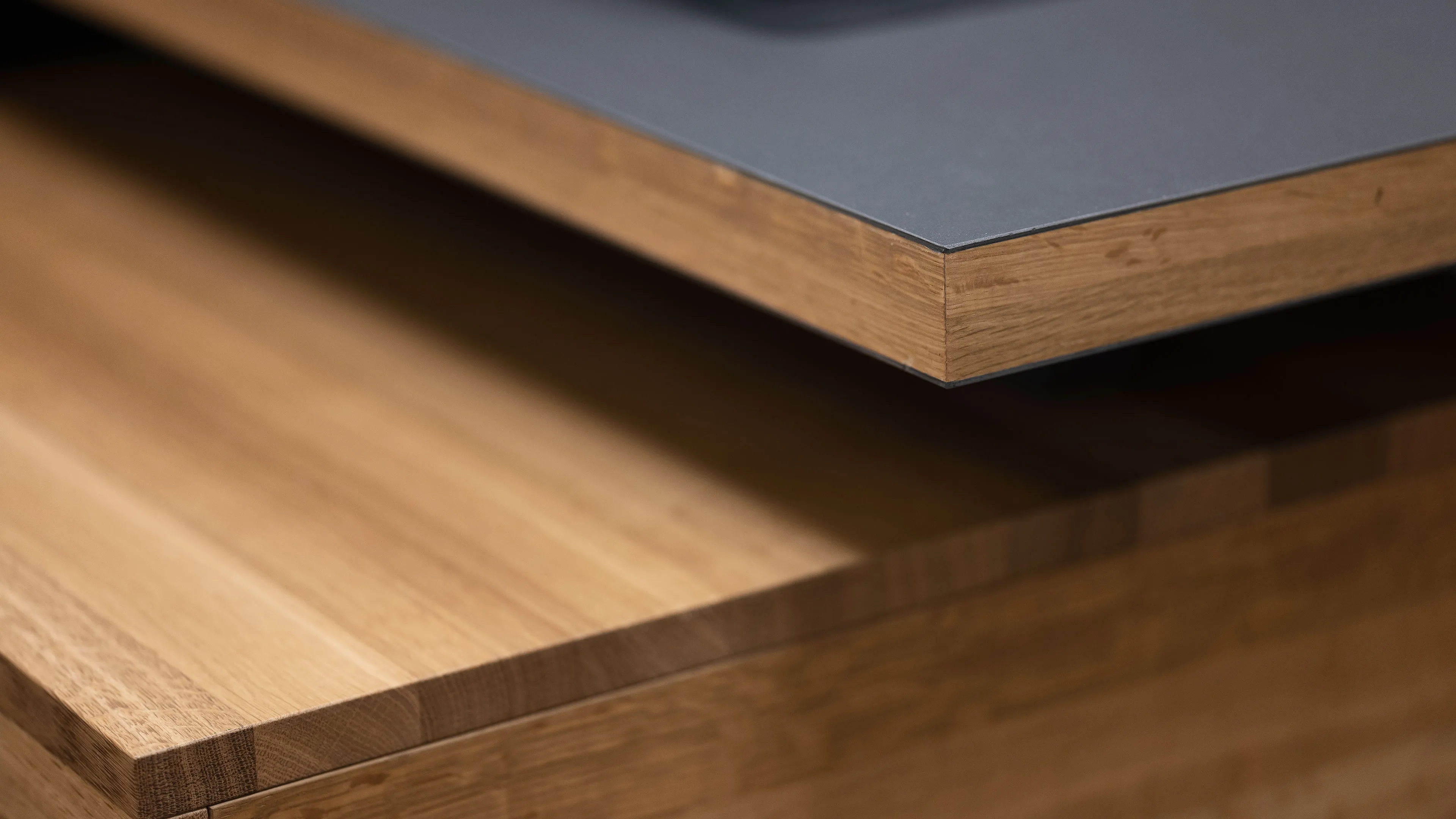 Close-up of two wooden tabletop edges, one with a black surface and the other plain wood.