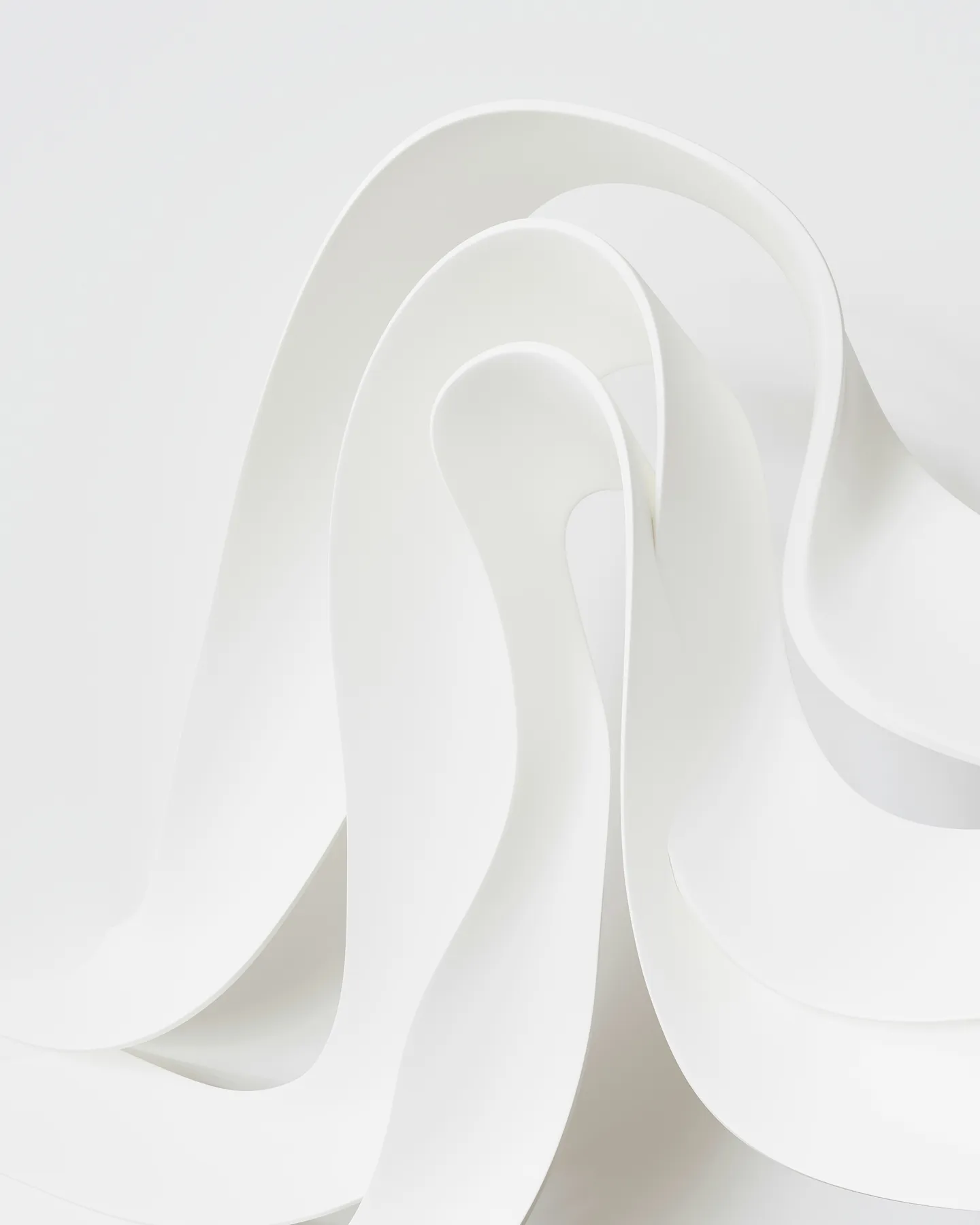 Abstract composition of smooth, flowing white curves and folds resembling layered ribbons.