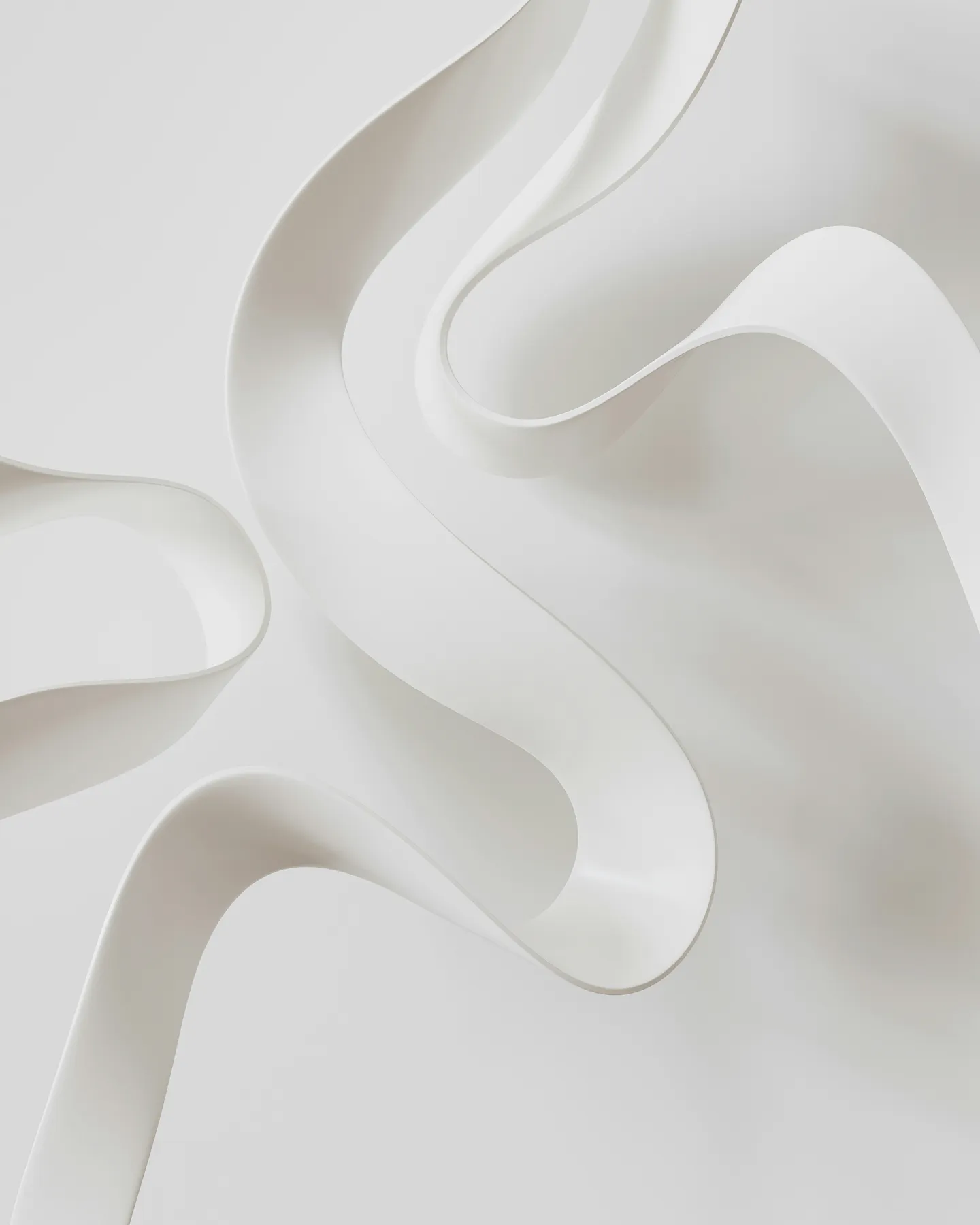 Abstract white smooth ribbons twisting over a white background creating soft shadows.