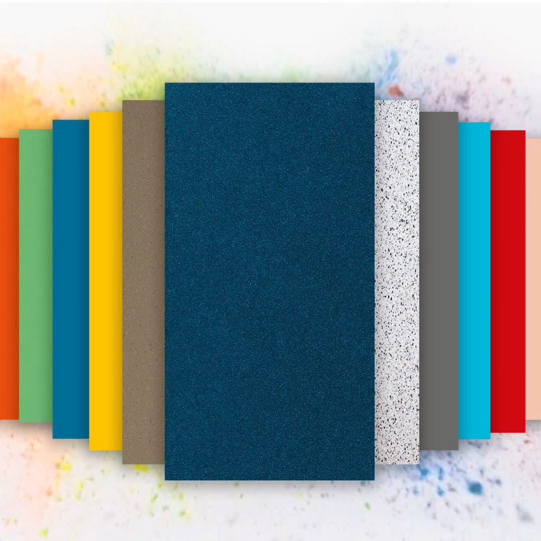 Array of rectangular solid color and textured material samples arranged side by side on a white surface with colorful powder splashes in the background.