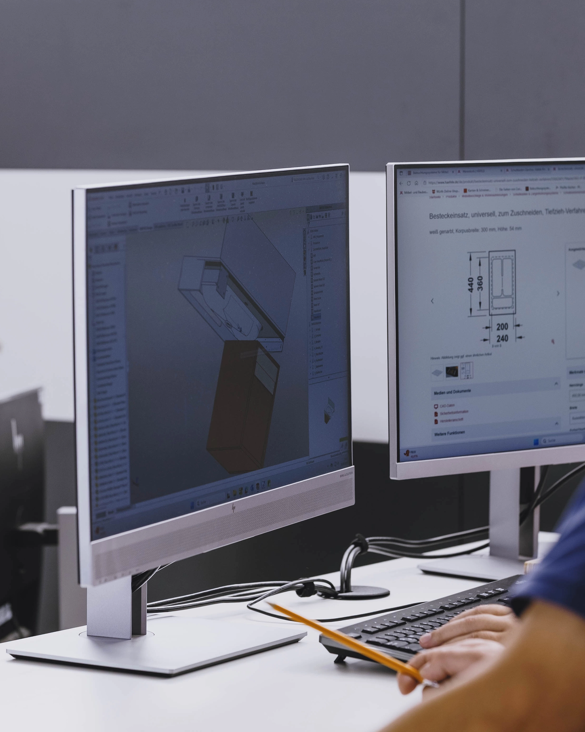 Person working at a desk with two monitors showing a 3D design and technical drawing.