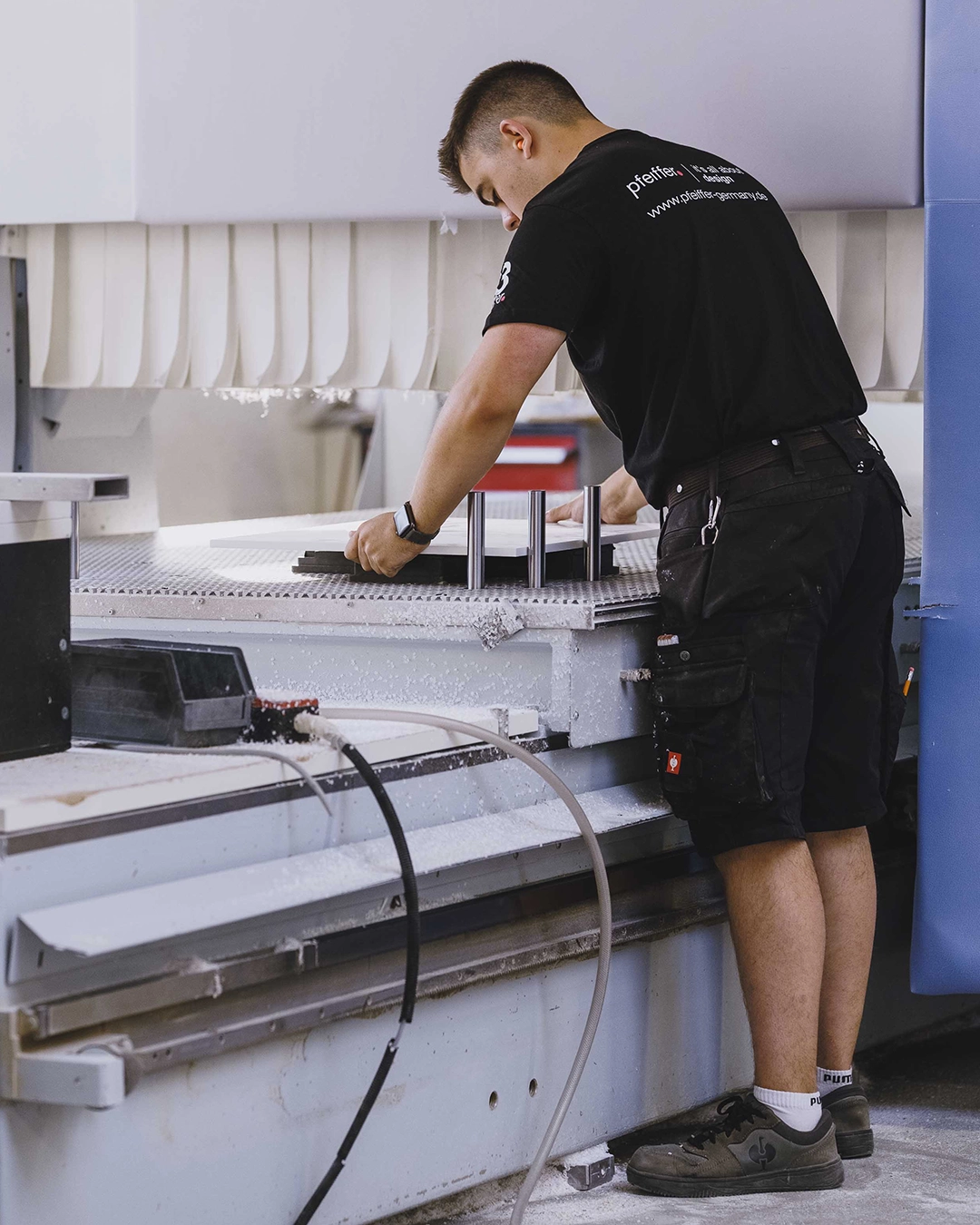 Man operating a large industrial machine, positioning a flat material on the machine's work surface.