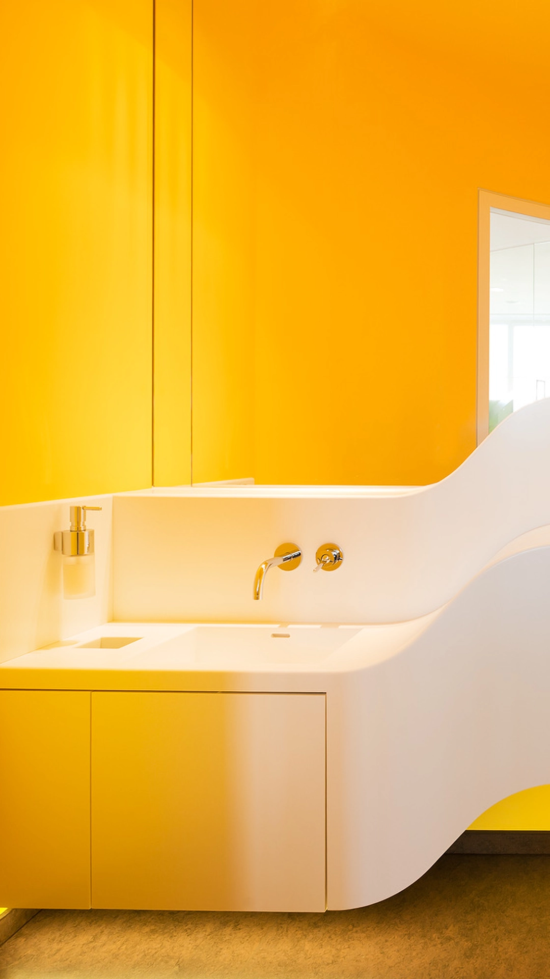Modern white bathroom sink with a curved design set against a vibrant yellow wall.