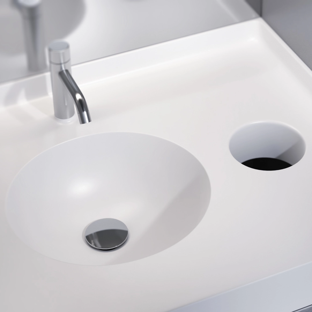 Modern white bathroom sink with a cylindrical chrome faucet and a round drain cover.