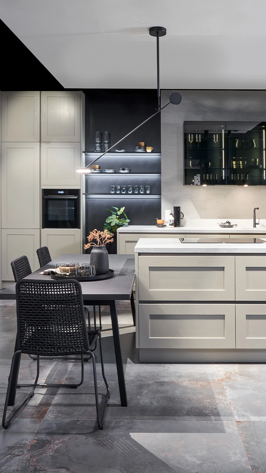 Moderne Küche mit hellem Holz, einer Kücheninsel, schwarzem Esstisch mit geflochtenen Stühlen und dekorativer Pendelleuchte.