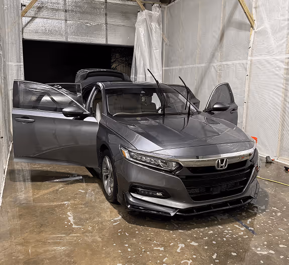 A sedan getting a full exterior and interior detail in a shop in Lafayette.