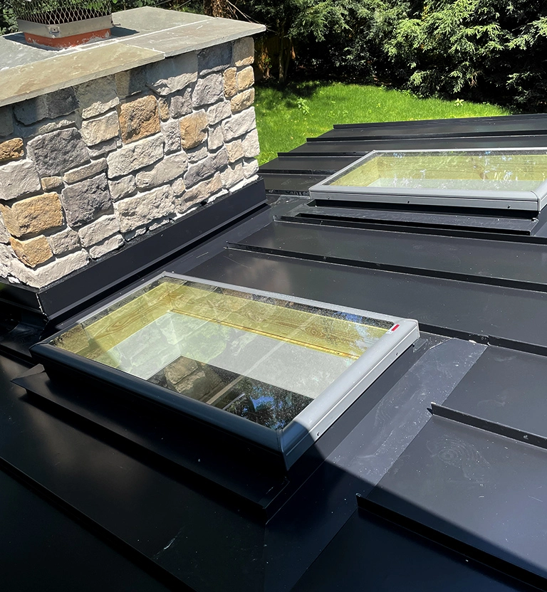 Black standing seam metal roof with 2 skylights and custom fabricated metal flashing in North Carolina