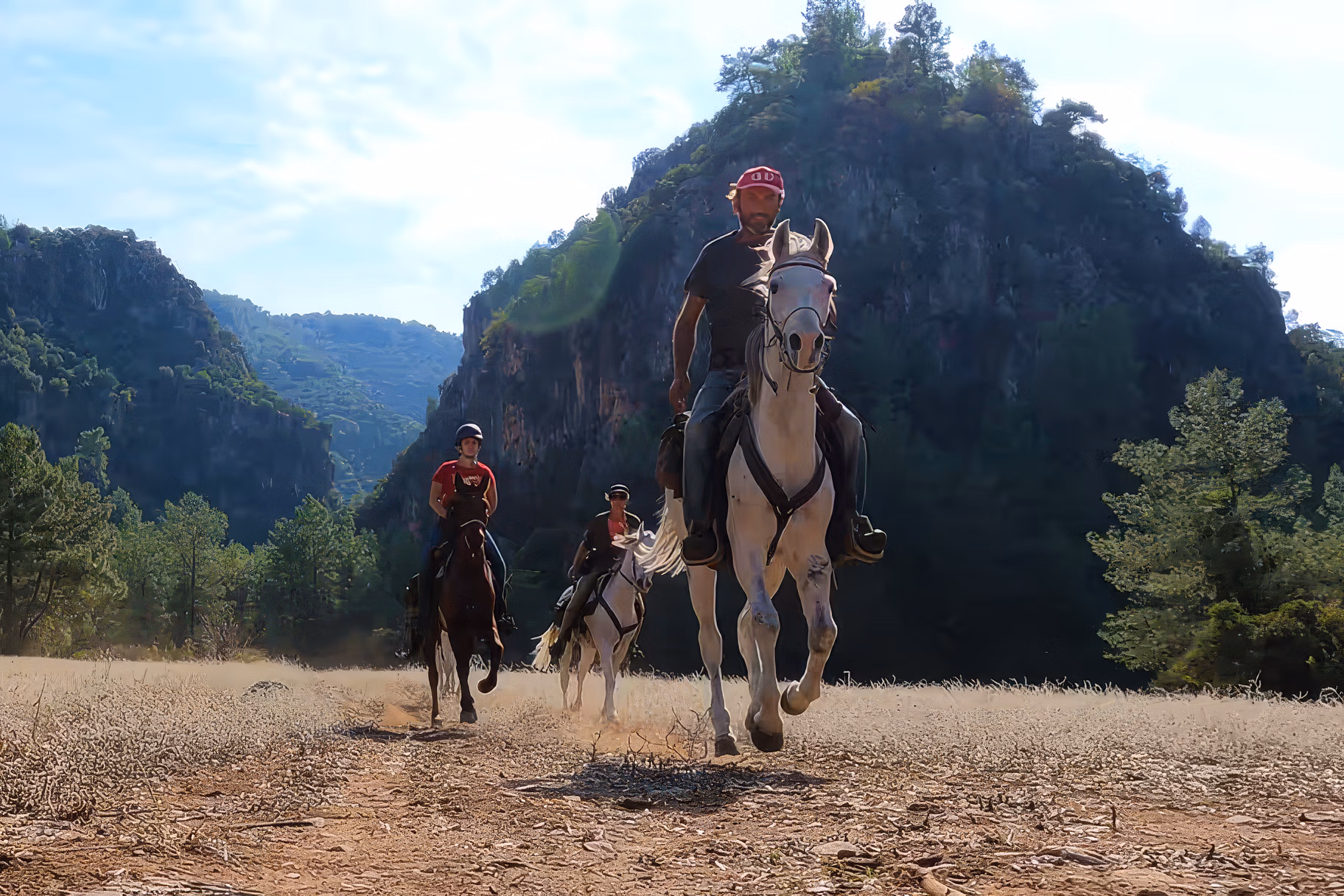 Three riders galloping away from unique rock formations