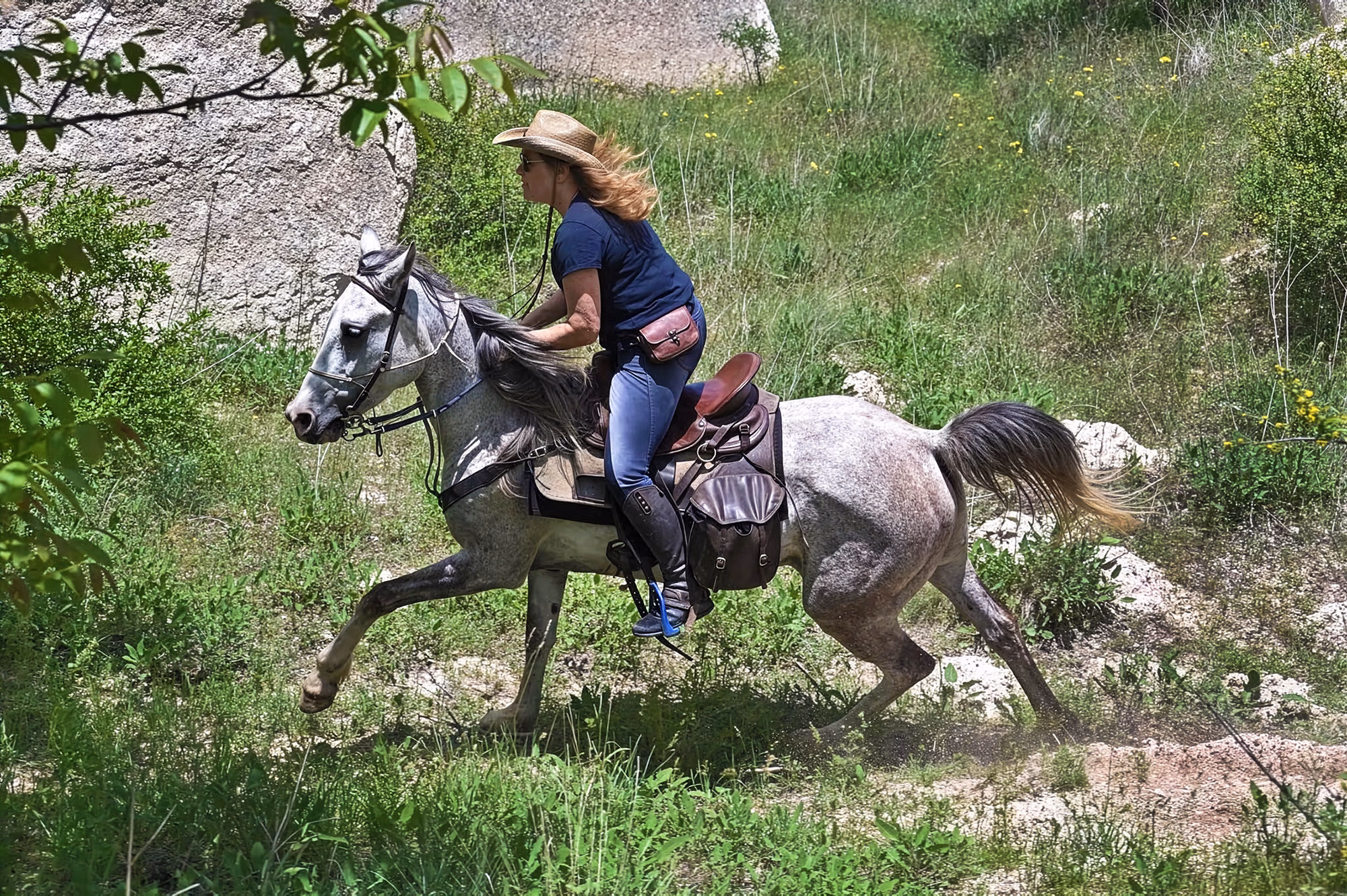 A woman riding a horse along a hill