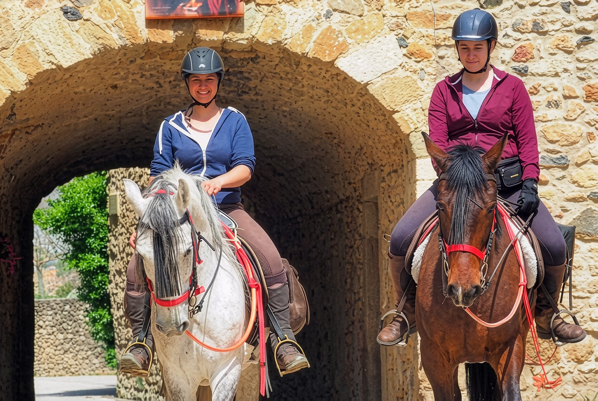 Rider and horse riding under old stone arches in traditional village Spain