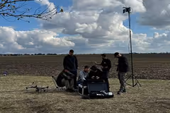 A group of people in a field with drones